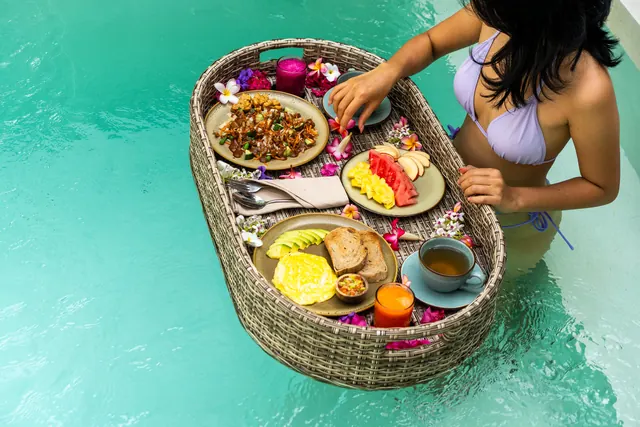 Guest with a floating breakfast basket in the villa pool